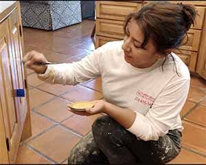 Paper Moon Painting artist Cristal working on cabinets