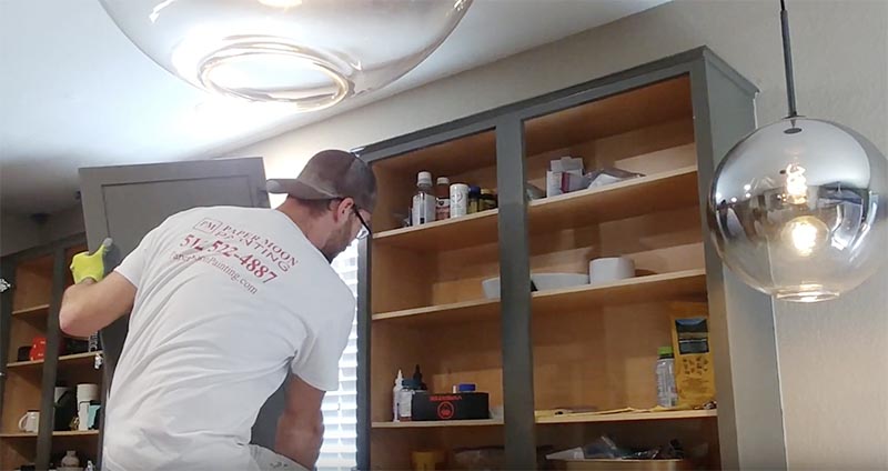 Cabinet painter reinstalling door after painting, Austin project