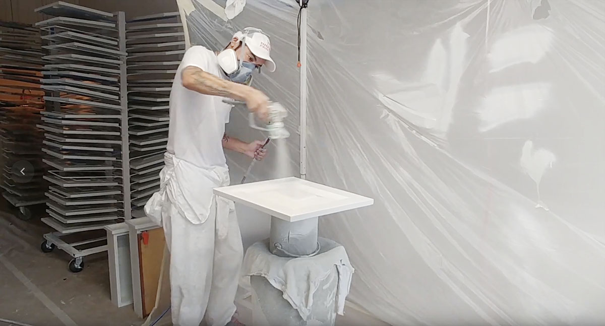 Pro painter spraying a white painted cabinet door, San Antonio, TX