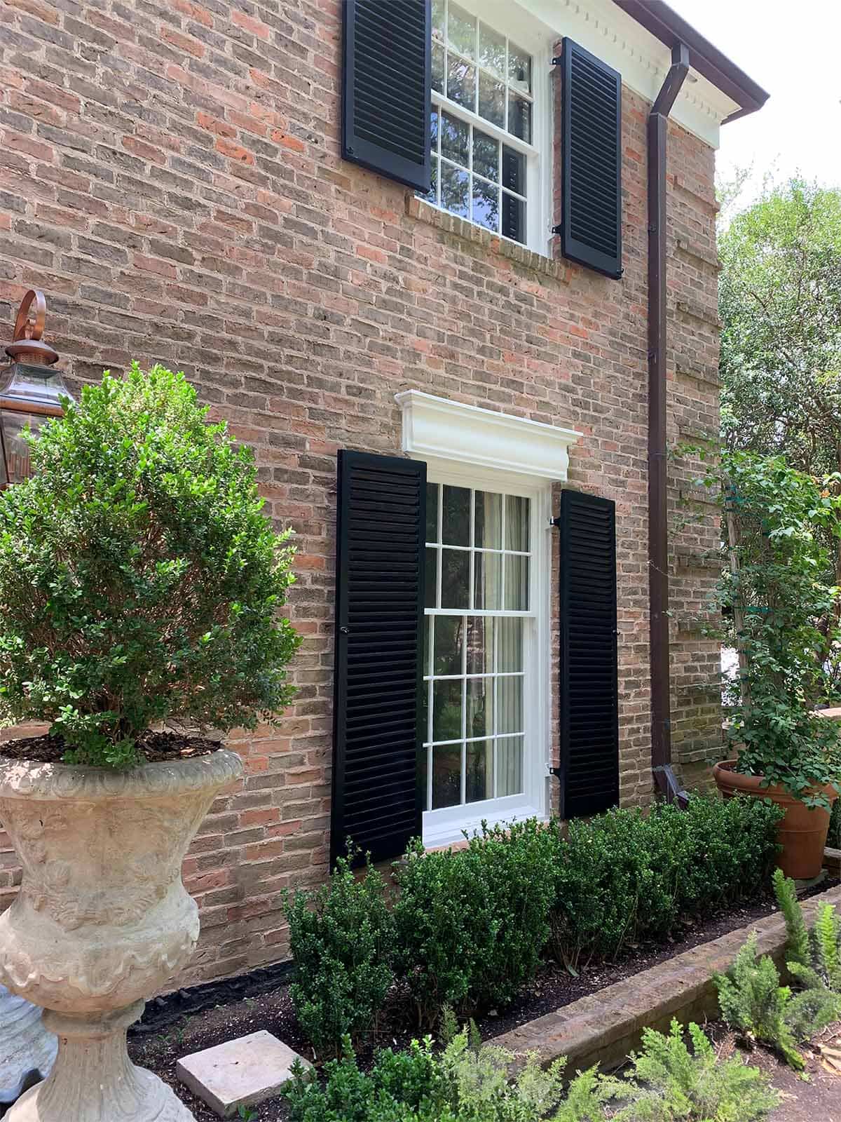 Corner of brick Alamo Heights exterior, shutter in Sherwin Williams Tricorn Black, trim in Benjamin Moore Pure White, TX home painter